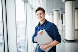 Handsome man holding a laptop in hall