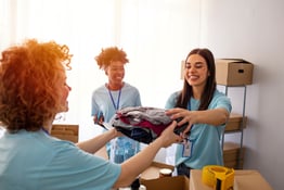 Volunteers pack canned goods into boxes during food drive. Helpful team of social workers. Group of mixed race people working in charitable foundation